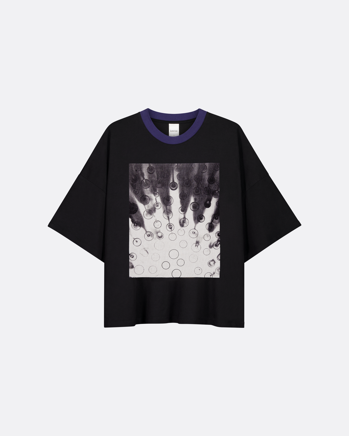 A black short-sleeve t-shirt with a blue ribbed crew neck and a square graphic print on the front featuring a black and white abstract design with circular details, displayed on a light gray background.
