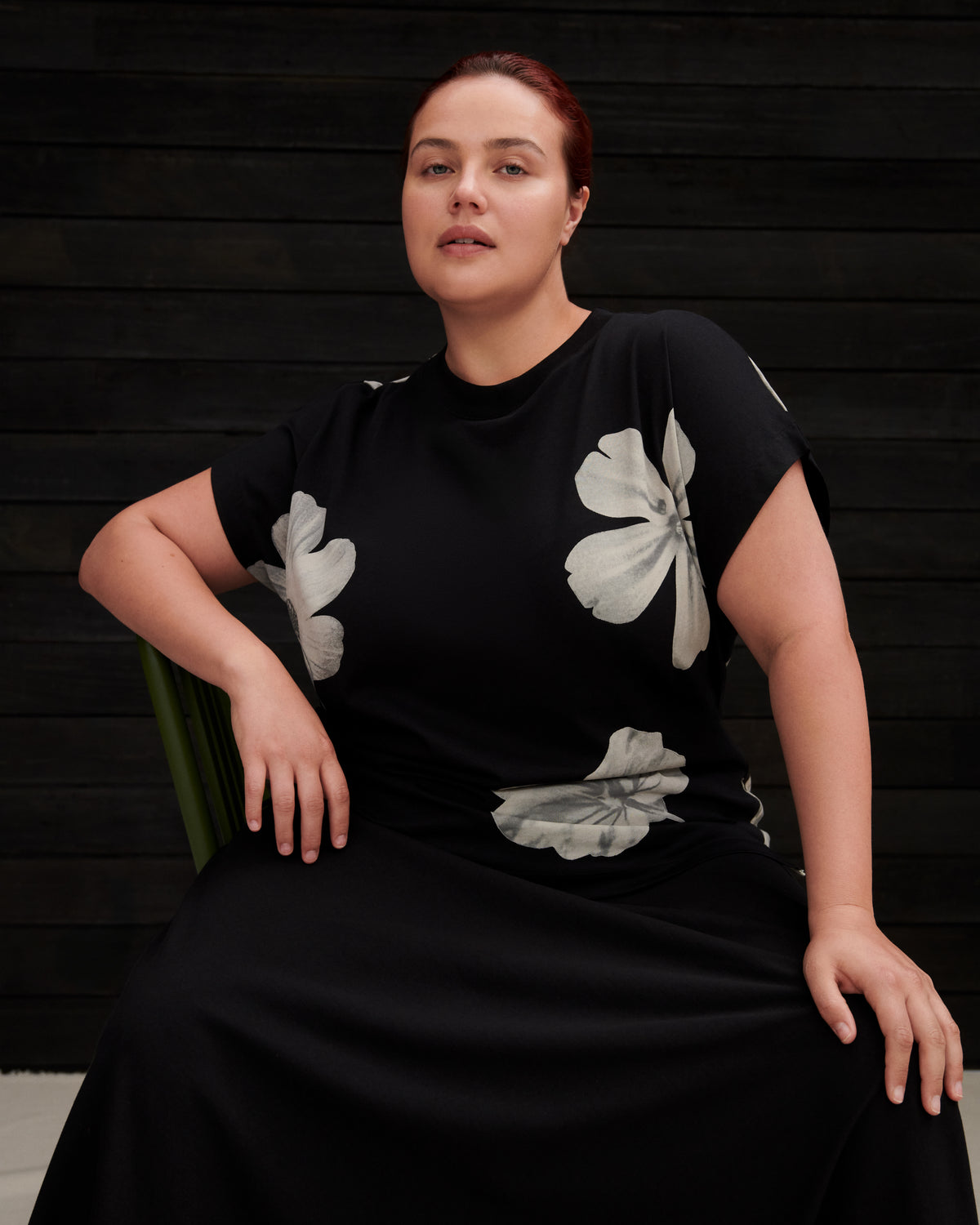 Woman wearing a black dress with white floral patterns against a dark wooden background