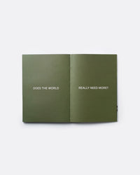 An open booklet or book spread on a light gray background, with olive green pages featuring the white text 'DOES THE WORLD' on the left page and 'REALLY NEED MORE?' on the right page.