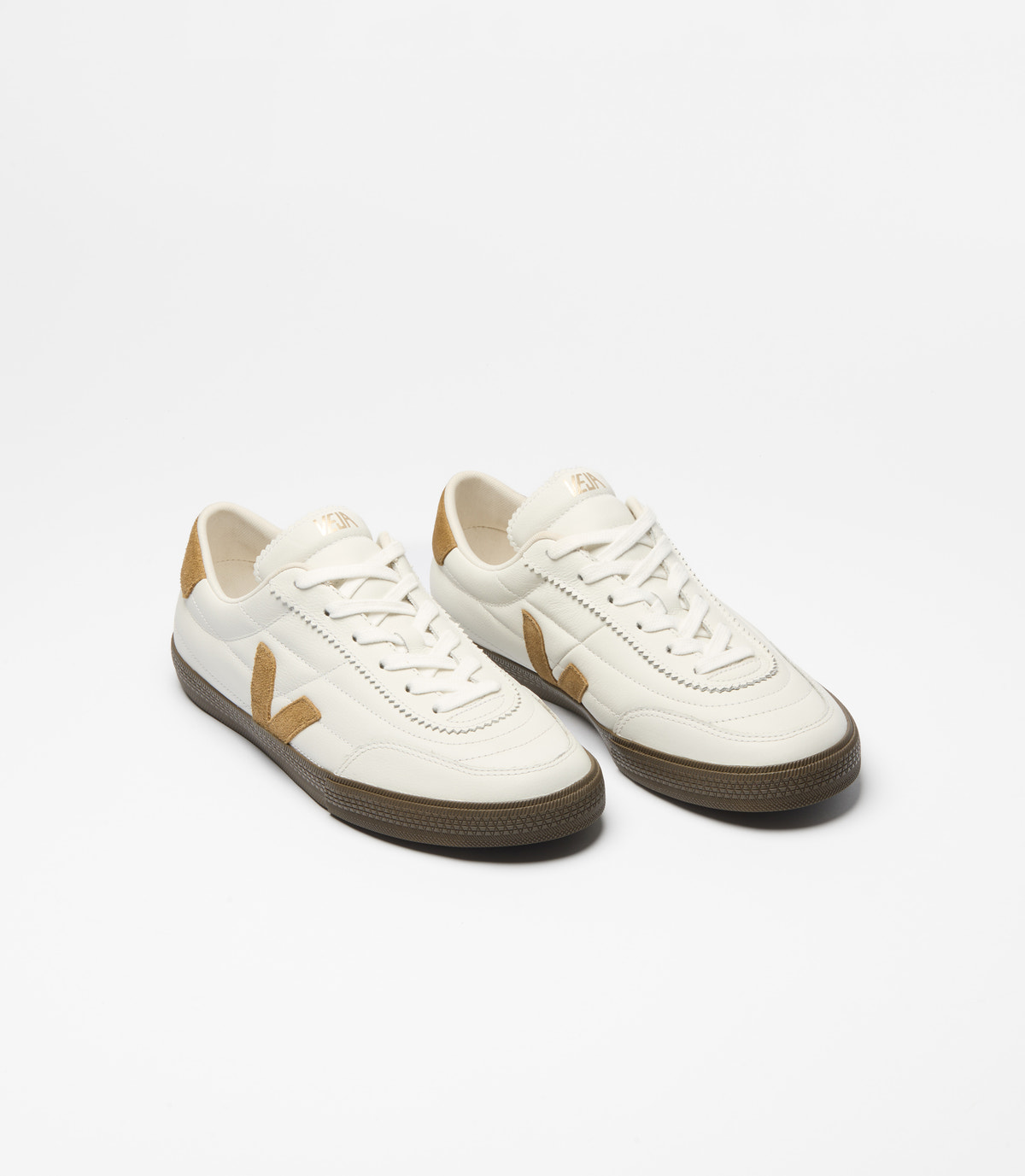 A pair of Veja low-top sneakers in off-white leather with tan accents and dark brown soles, shown on a clean white background.