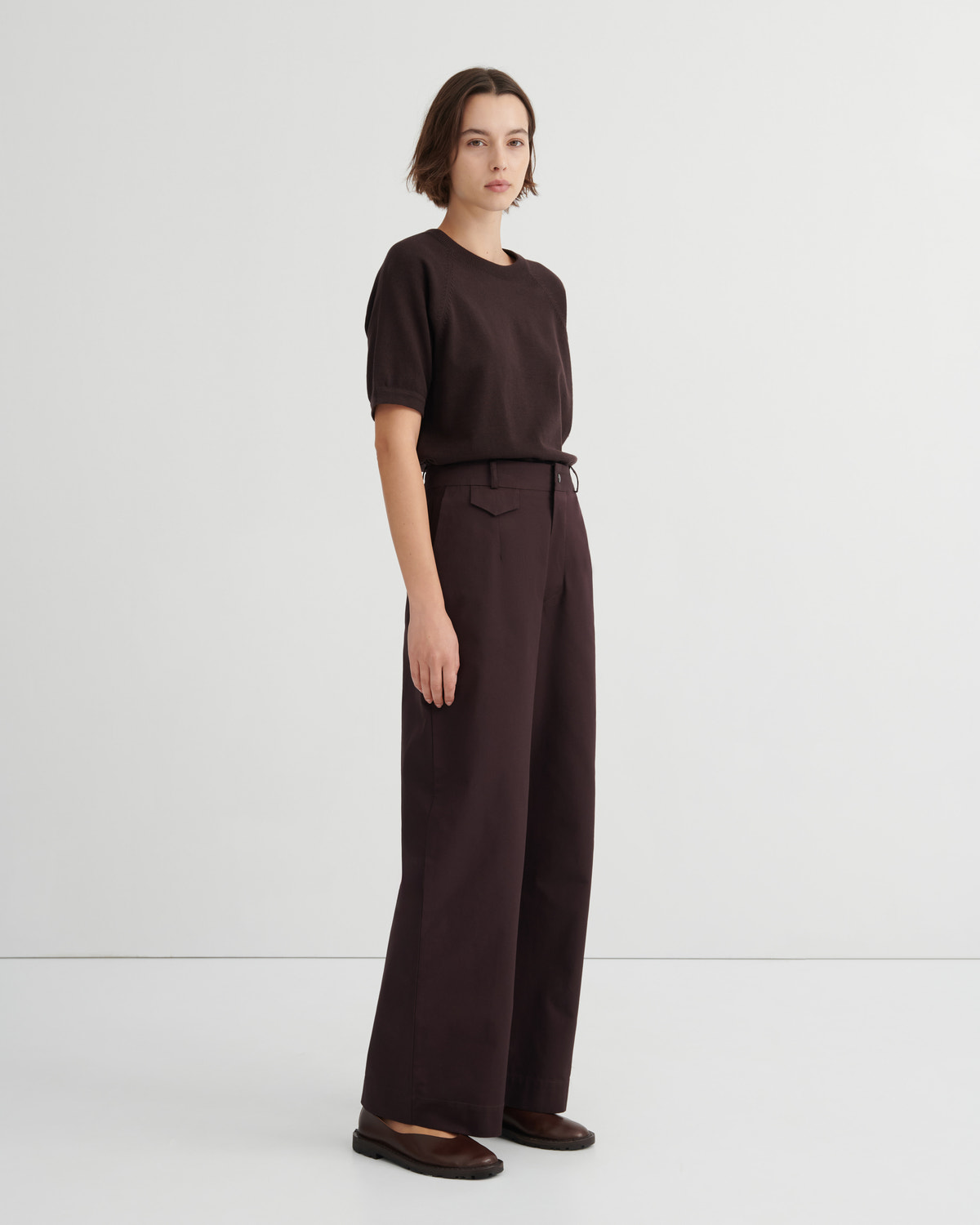A model wearing a dark brown short-sleeve t-shirt and matching dark brown wide-leg trousers paired with dark brown flats.