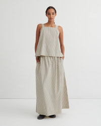 A model stands against a plain white studio background wearing a sleeveless beige and white vertically striped two-piece set consisting of a cropped top and wide-leg skirt.