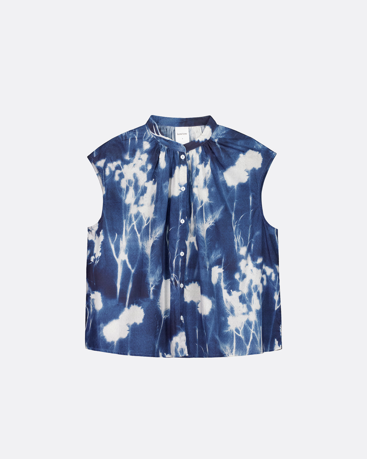 A sleeveless button-front top with a stand collar, featuring a blue and white shibori tie-dye pattern, displayed flat against a light gray background.