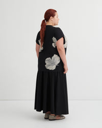 Woman wearing a black dress with floral patterns on a white background