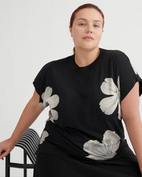 Woman wearing a black t-shirt with white floral patterns on a plain background