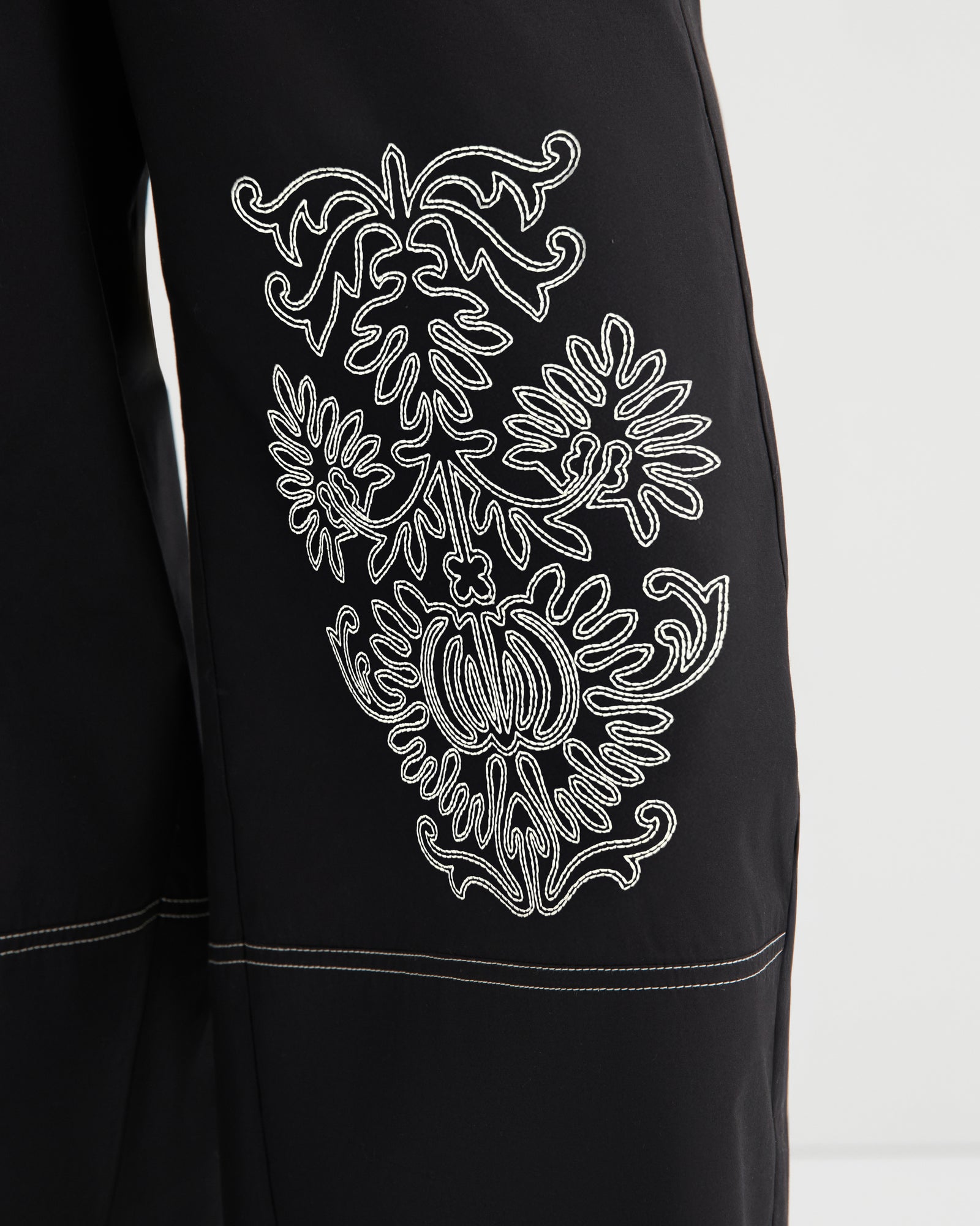 Black garment with white embroidered design on a white background