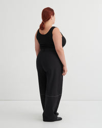 Person wearing a black tank and black pants against a white background