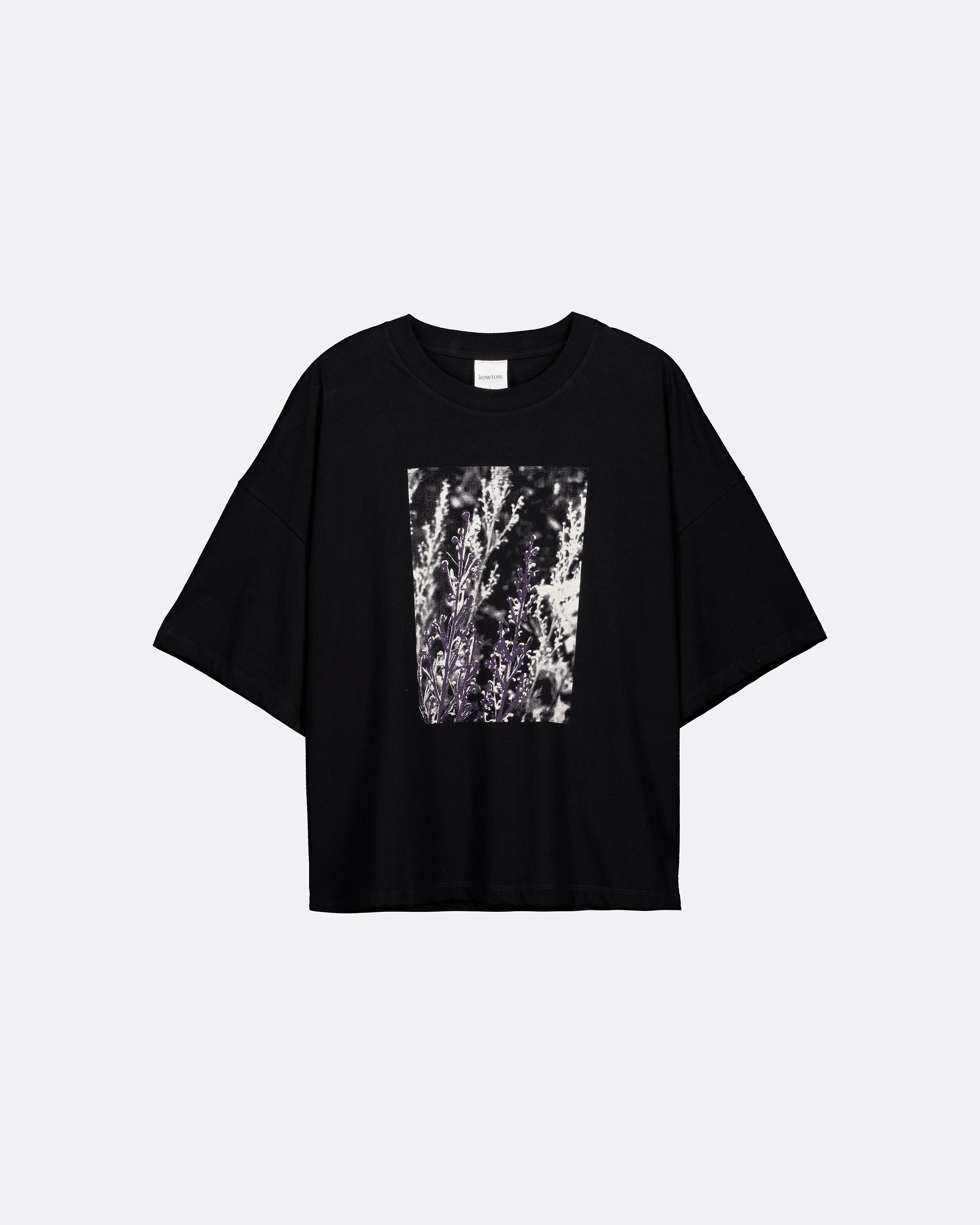 A black short-sleeve t-shirt with a square abstract graphic print in black, white, and gray on the front, displayed against a light gray background.