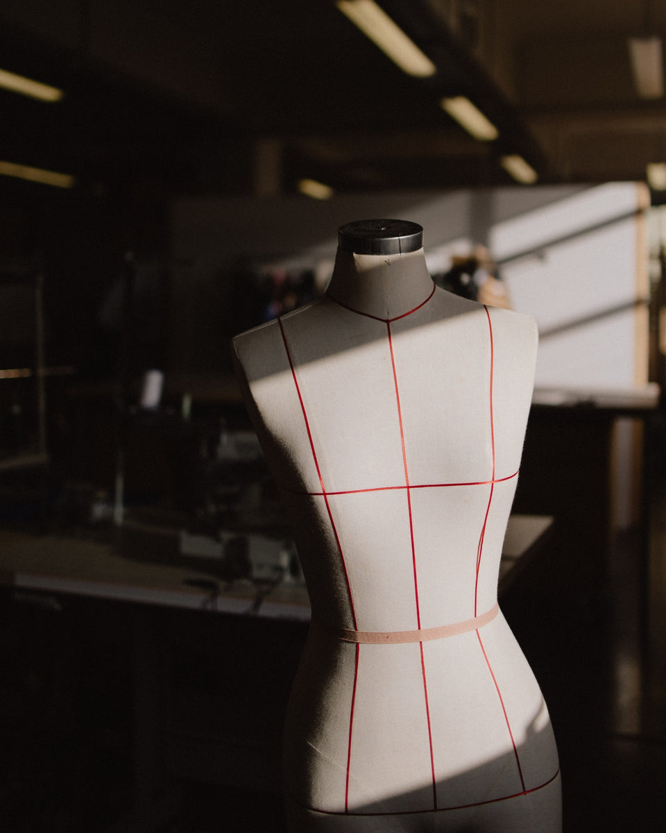A photo of a mannequin sitting in a sewing studio.