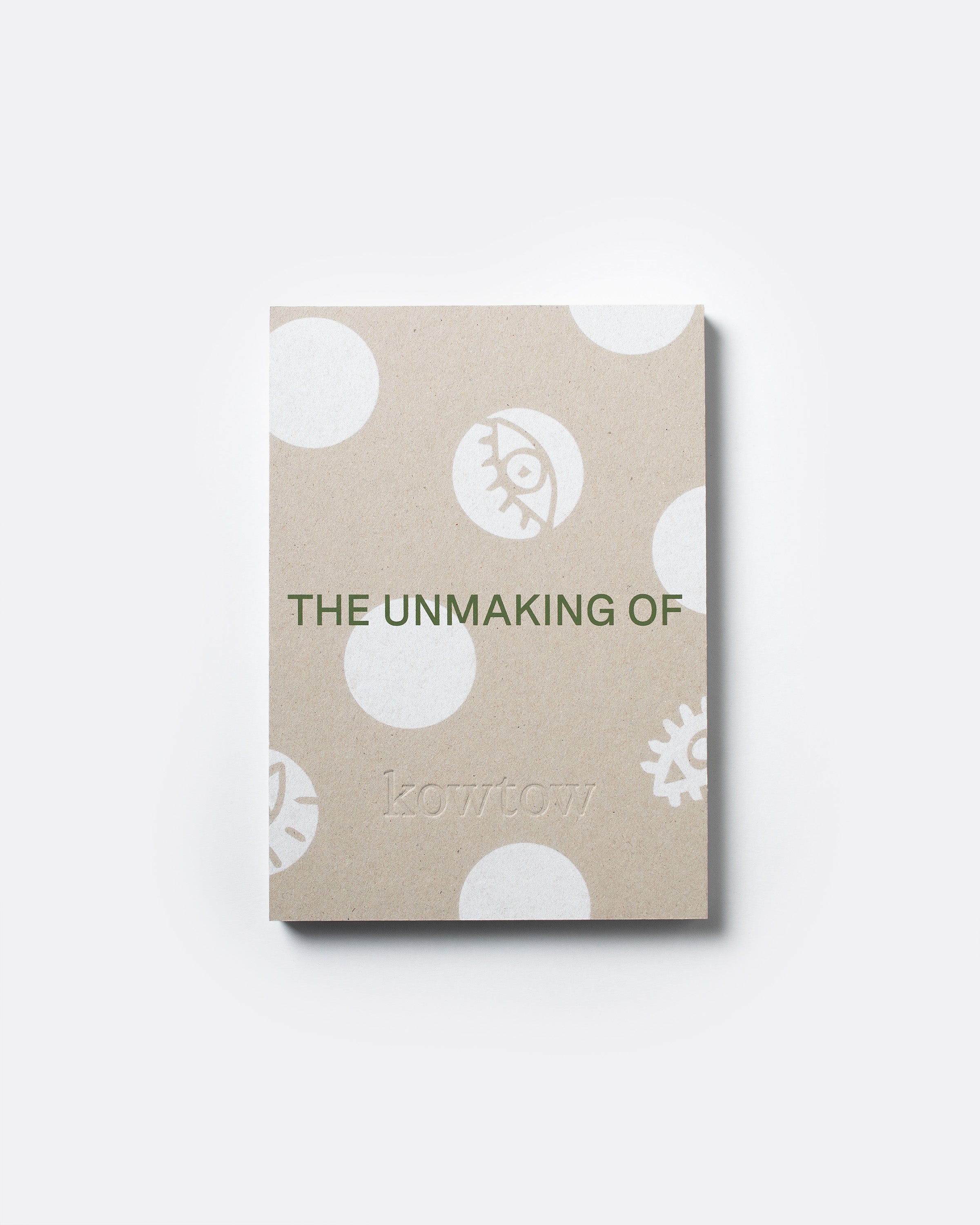 A square kraft paper notebook or book cover with white polka dots and minimalist illustrations, featuring the text 'THE UNMAKING OF' and the brand name 'kowtow' in green, shown on a light gray background.