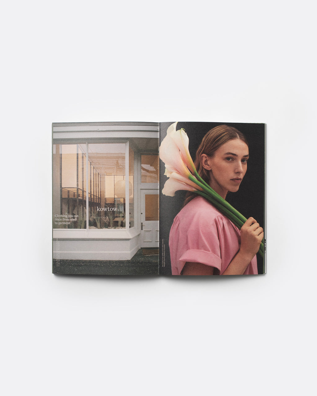 An open magazine or book spread displayed against a light gray background. The left page shows a modern glass-front building interior, and the right page features a woman in a pink top holding large pale pink-and-white calla lilies against a dark background.