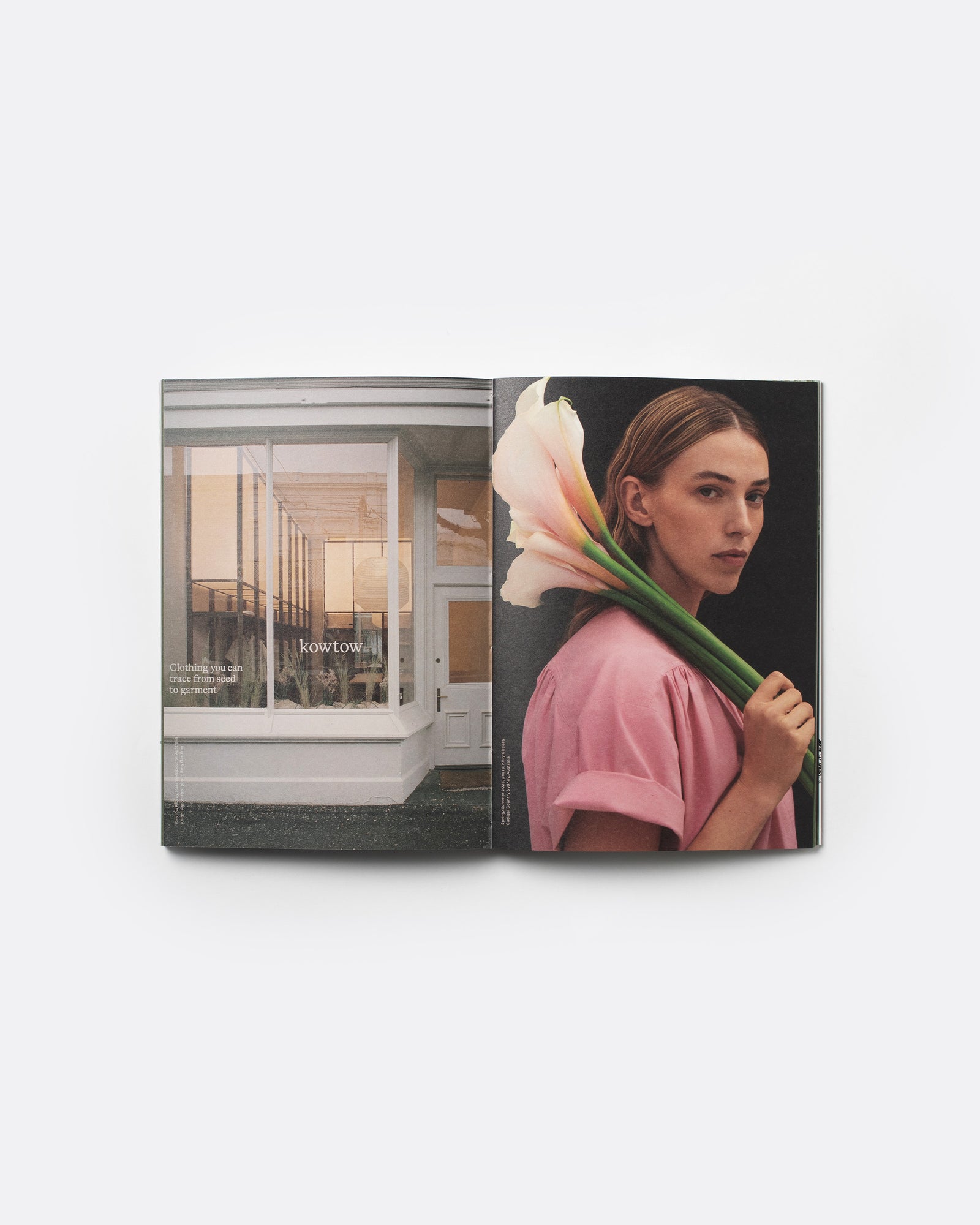 An open magazine or book spread displayed against a light gray background. The left page shows a modern glass-front building interior, and the right page features a woman in a pink top holding large pale pink-and-white calla lilies against a dark background.