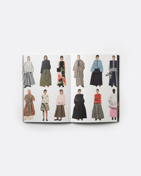 An open fashion magazine or book spread displaying multiple illustrated models wearing different outfits, photographed against a clean white background.