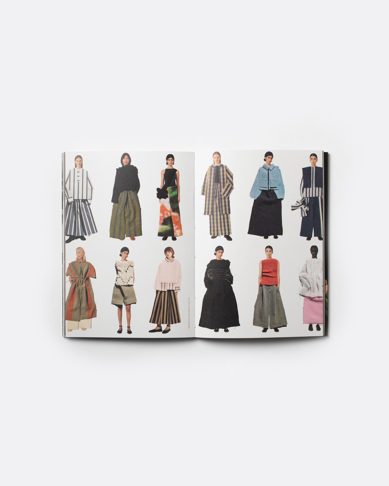 An open fashion magazine or book spread displaying multiple illustrated models wearing different outfits, photographed against a clean white background.