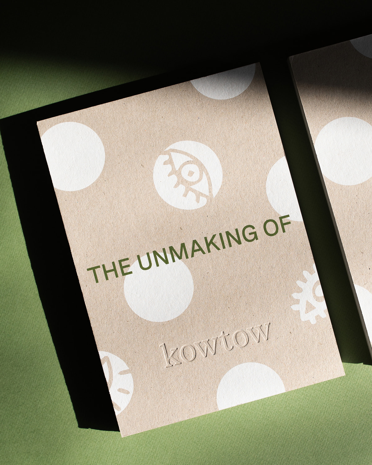 Cover of a book with 'the unmaking of' and 'kowtow' embossed, sitting on a green backdrop.