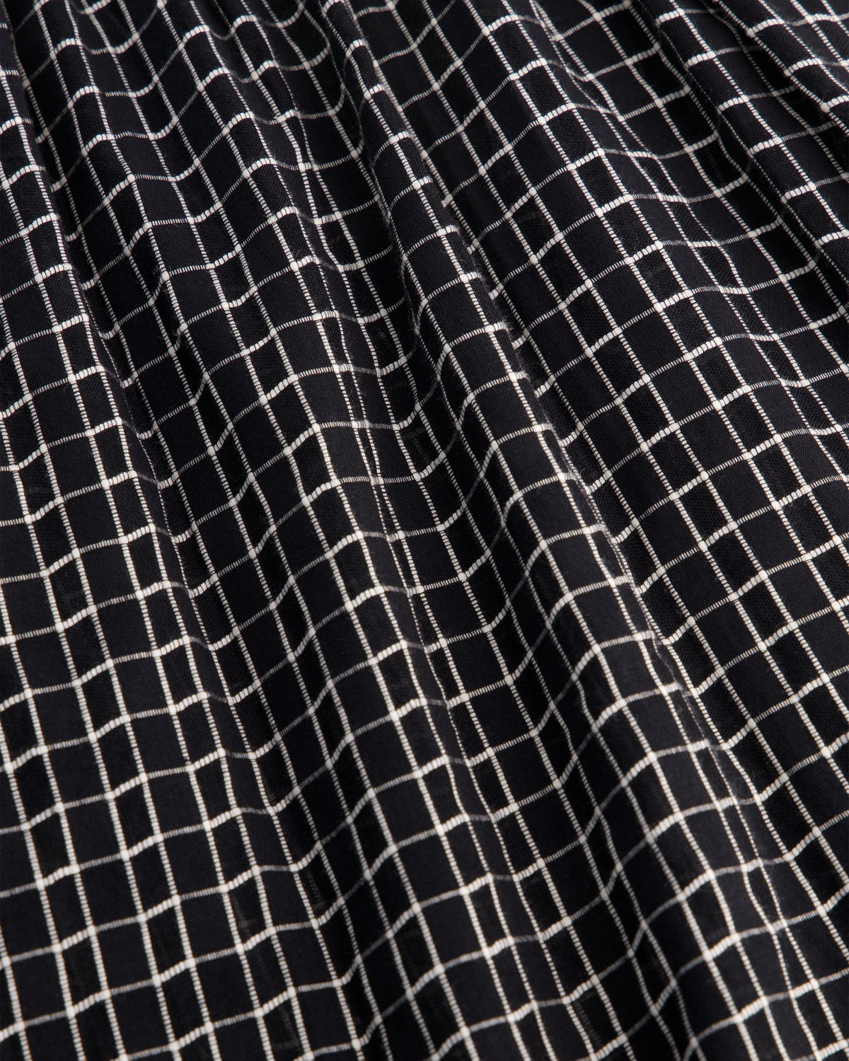 Close-up of a black fabric with a white grid pattern, showing the texture and weave.