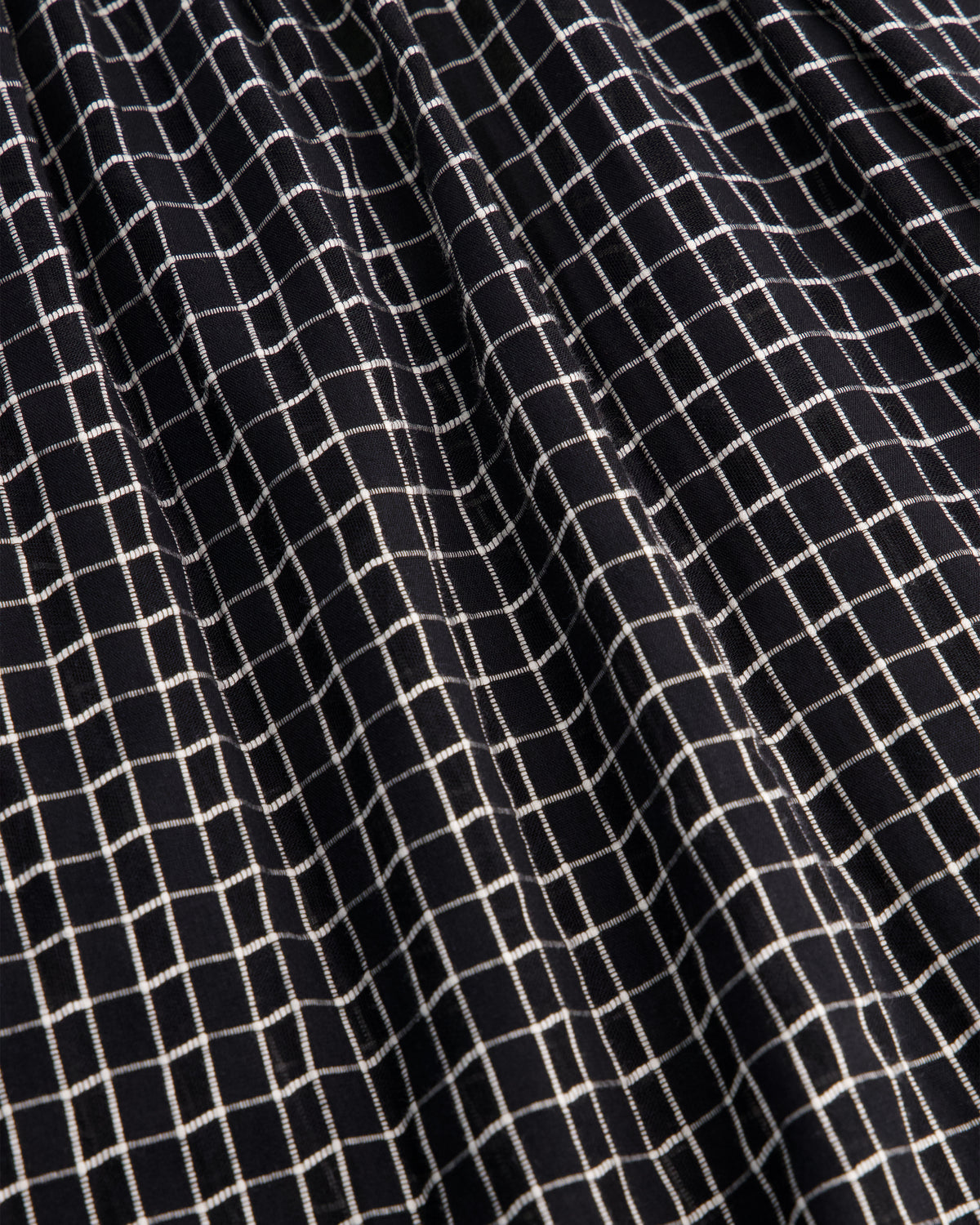 Close-up of a black fabric with a white grid pattern, showing the texture and weave.