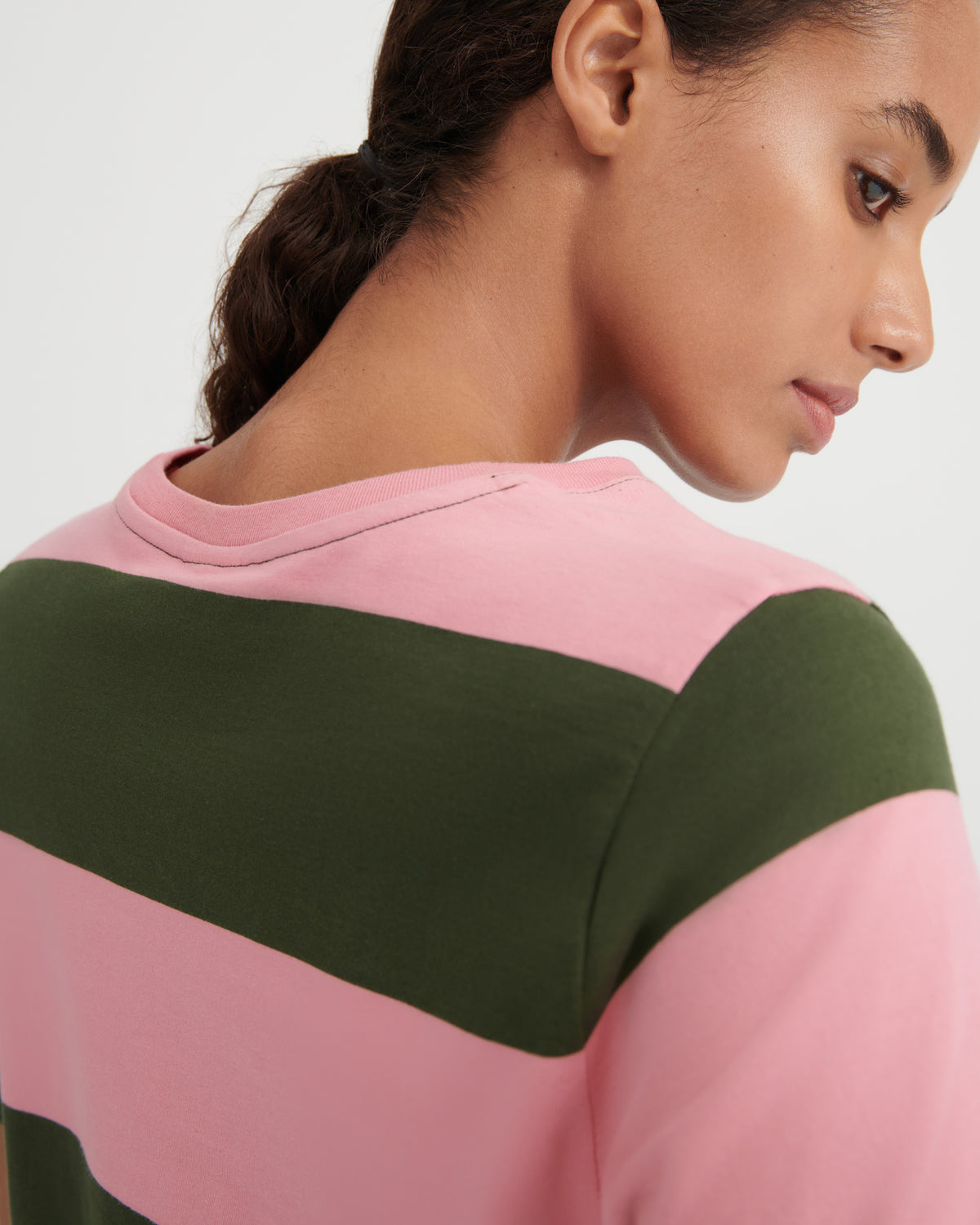 Person wearing a pink and green striped shirt on a white background
