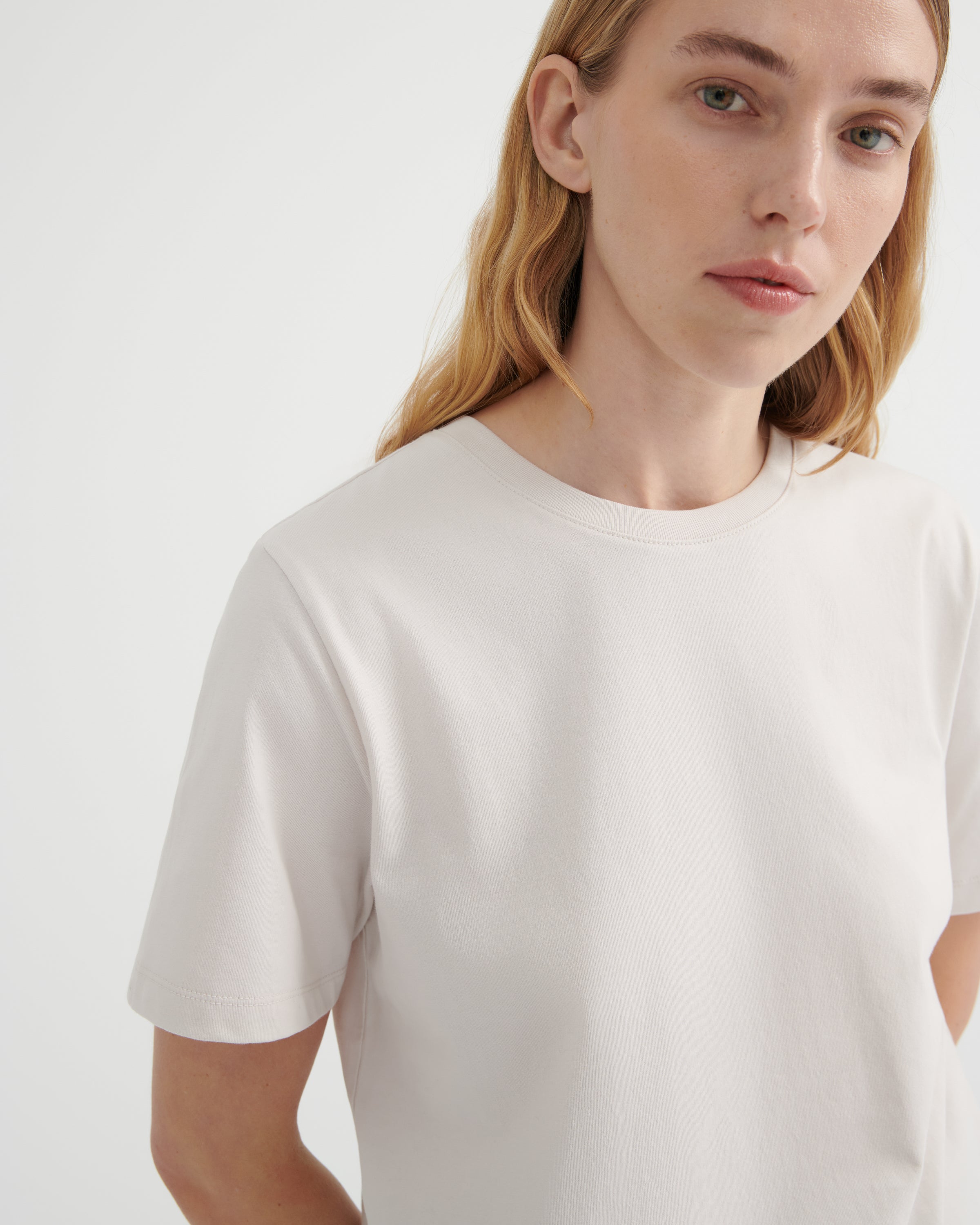 A close-up shot of a woman wearing an off-white crew-neck t-shirt.