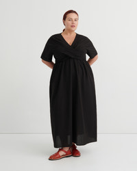 A women wears a black v-neck dress and red sandals.
