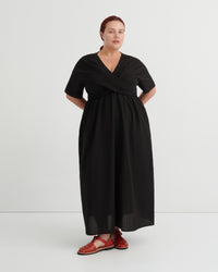 A women wears a black v-neck dress and red sandals.