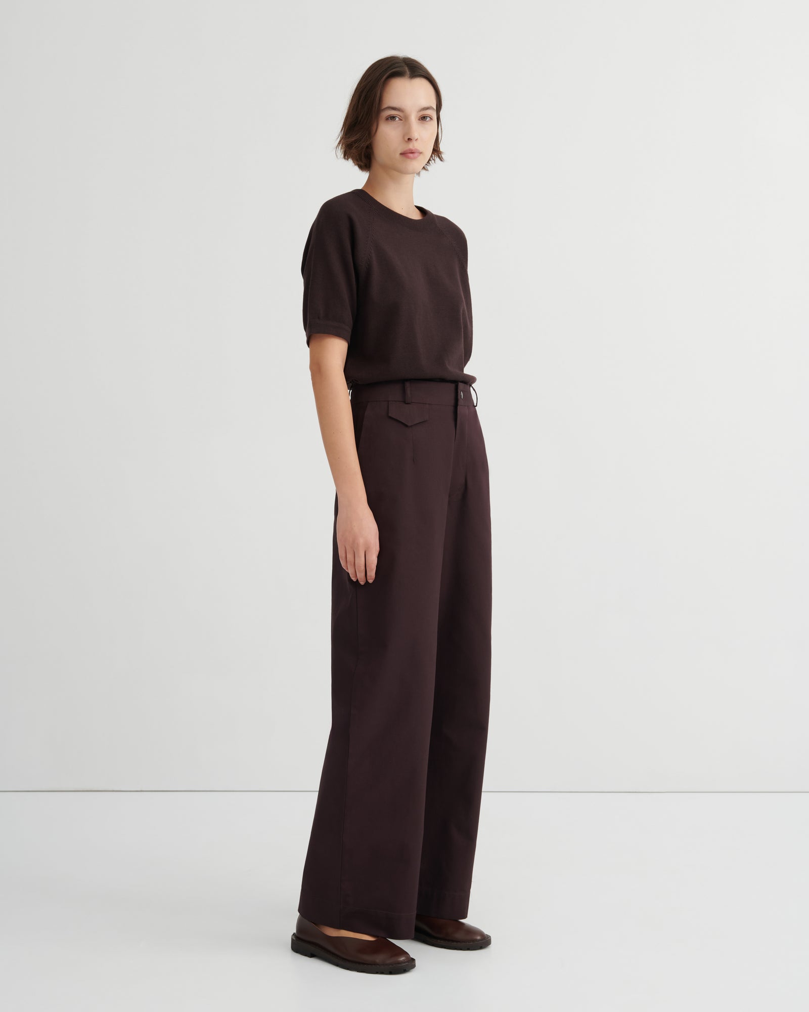 A model wearing a dark brown short-sleeve t-shirt and matching dark brown wide-leg trousers paired with dark brown flats.
