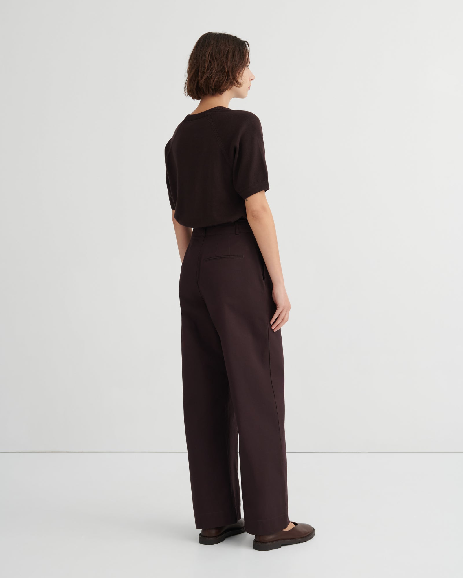 A model shown from the back wearing a dark brown short-sleeve top and matching dark brown wide-leg trousers.