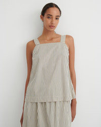 A model wearing a sleeveless top and matching wide-leg pants set in a cream and dark green vertical stripe pattern, photographed against a plain white wall.