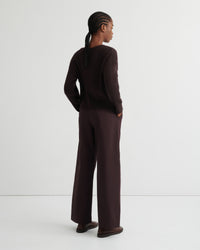 A model is shown from the back wearing a dark brown ribbed knit long-sleeve top and matching wide-leg trousers, standing against a clean white studio background.