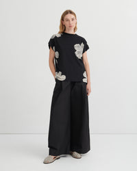 Person wearing a black outfit with floral patterns on a white background
