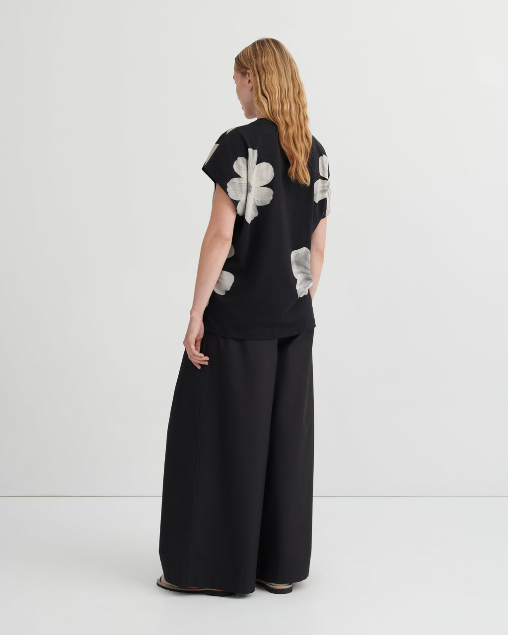 Woman wearing a black outfit with white floral patterns on a white background