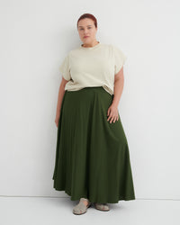 Person wearing a beige top and green skirt on a white background
