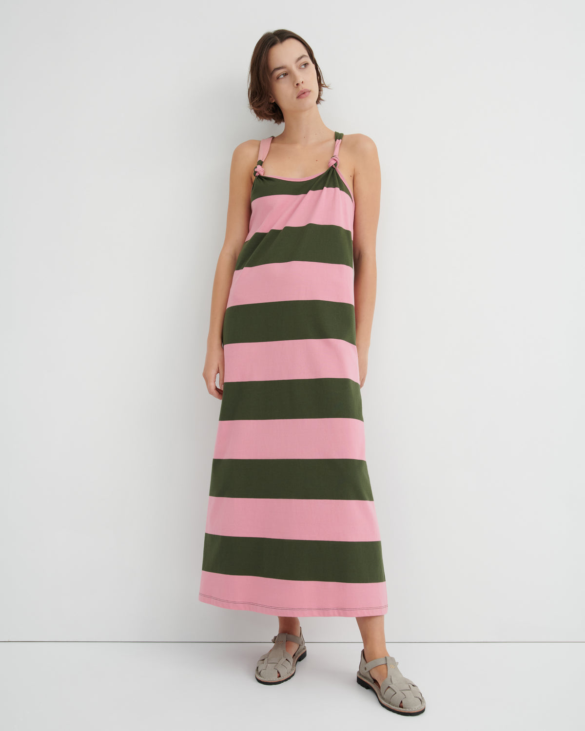 Woman wearing a pink and green striped dress against a white background