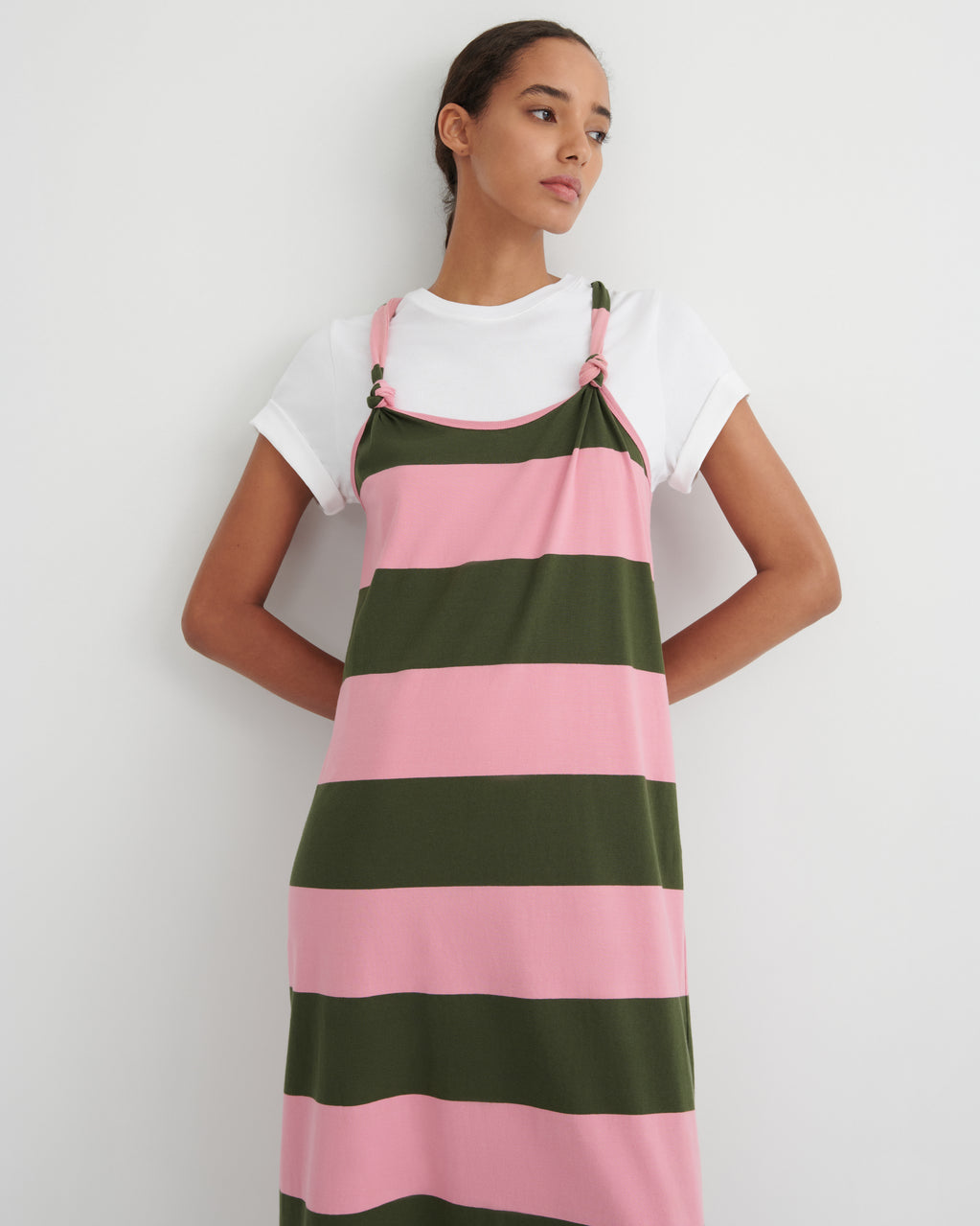 Woman wearing a pink and green striped dress over a white shirt on a plain background