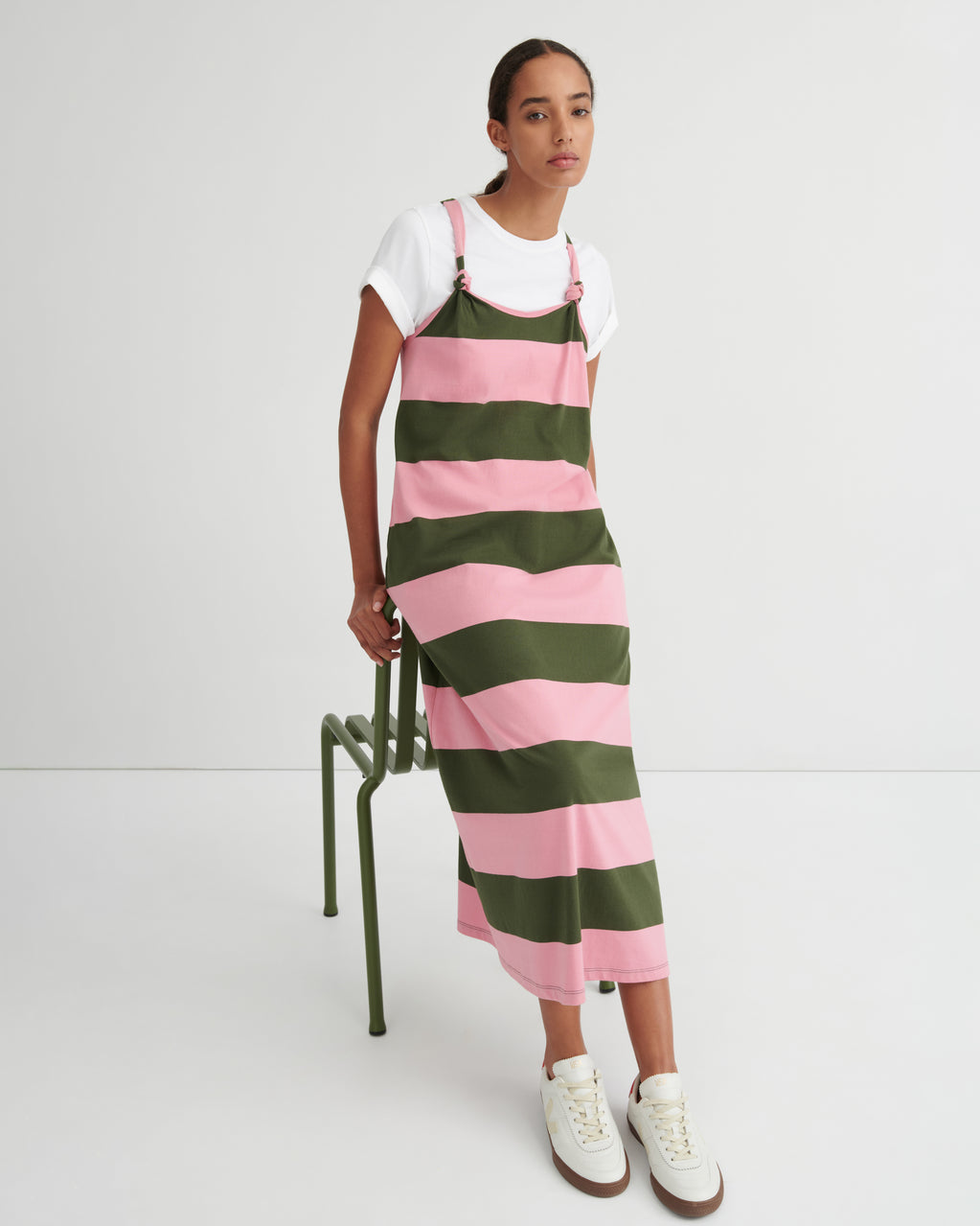 Person wearing a green and pink striped dress over a white shirt on a white background