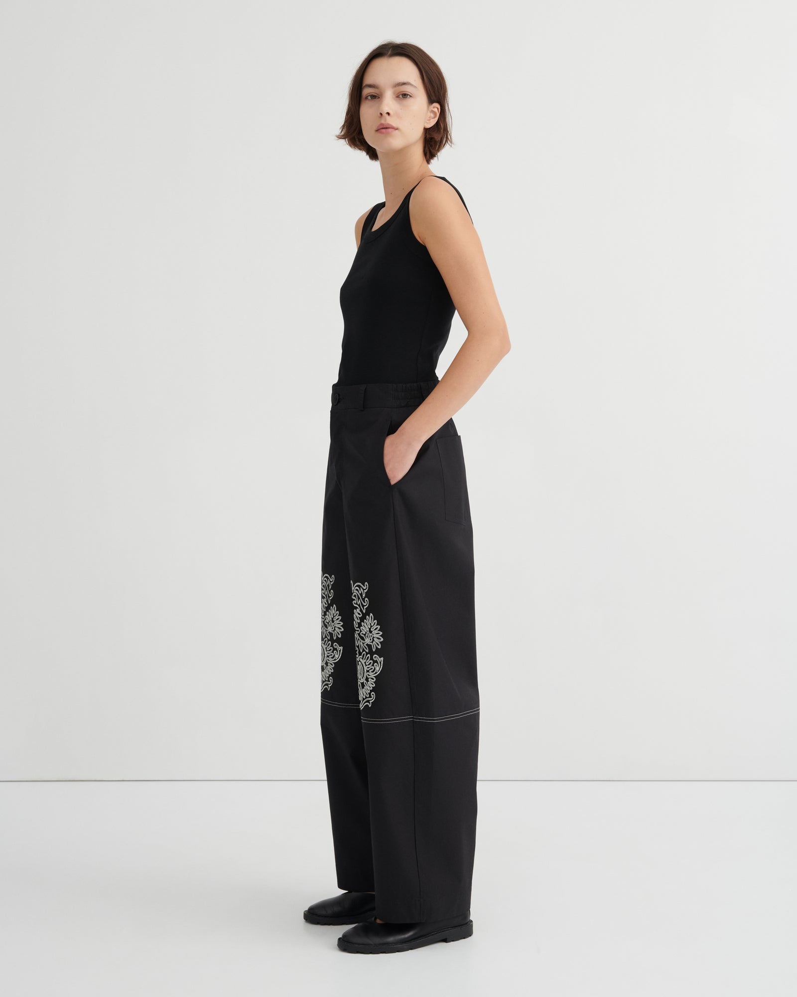Woman wearing a black outfit with floral embroidery on a white background