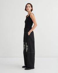 Woman wearing a black outfit with floral embroidery on a white background