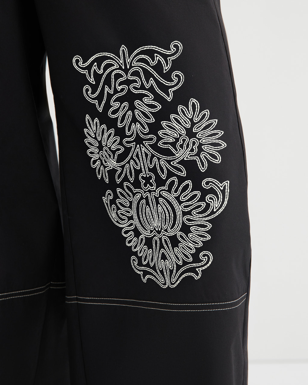 Black garment with white embroidered design on a white background