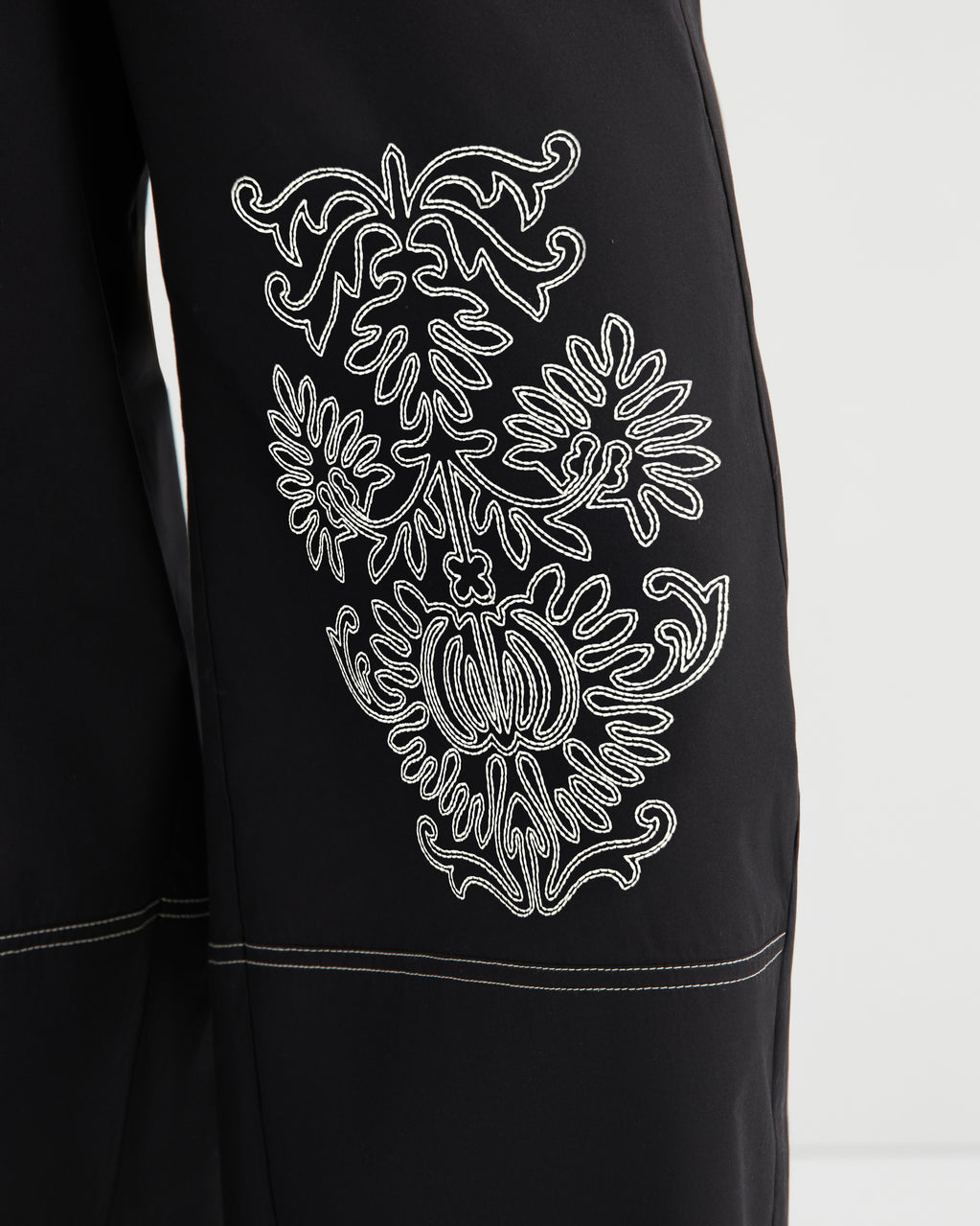 Black garment with white embroidered design on a white background