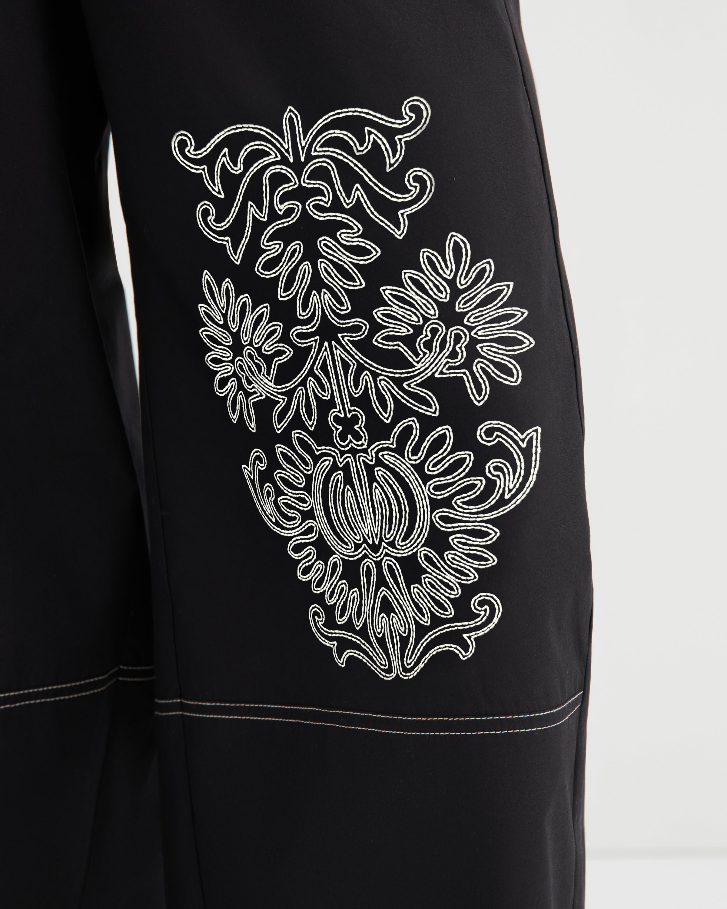 Black garment with white embroidered design on a white background