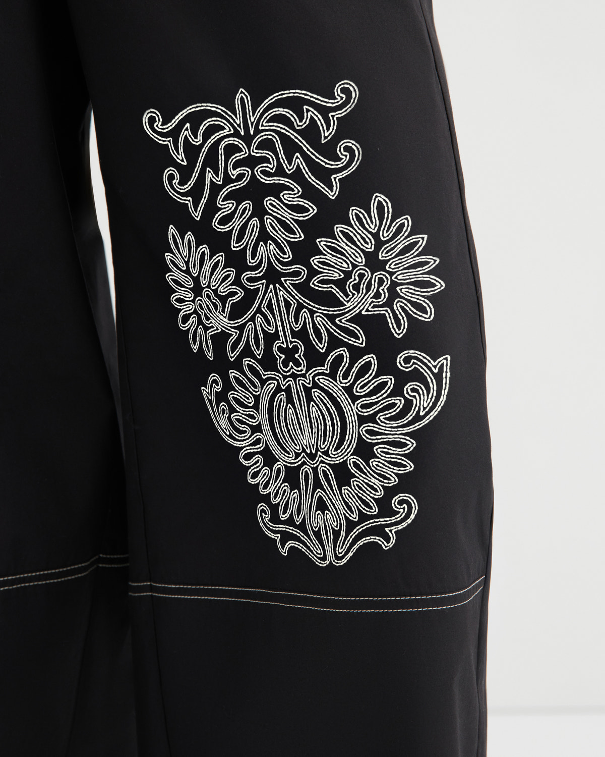 Black garment with white embroidered design on a white background