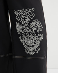 Black garment with white embroidered design on a white background