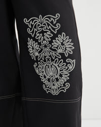 Black garment with white embroidered design on a white background