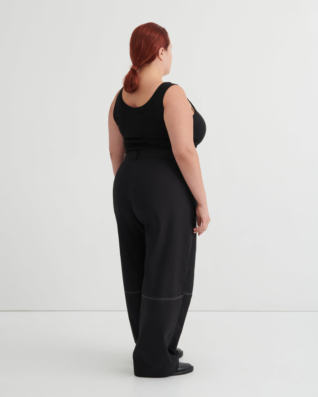 Person wearing a black tank and black pants against a white background