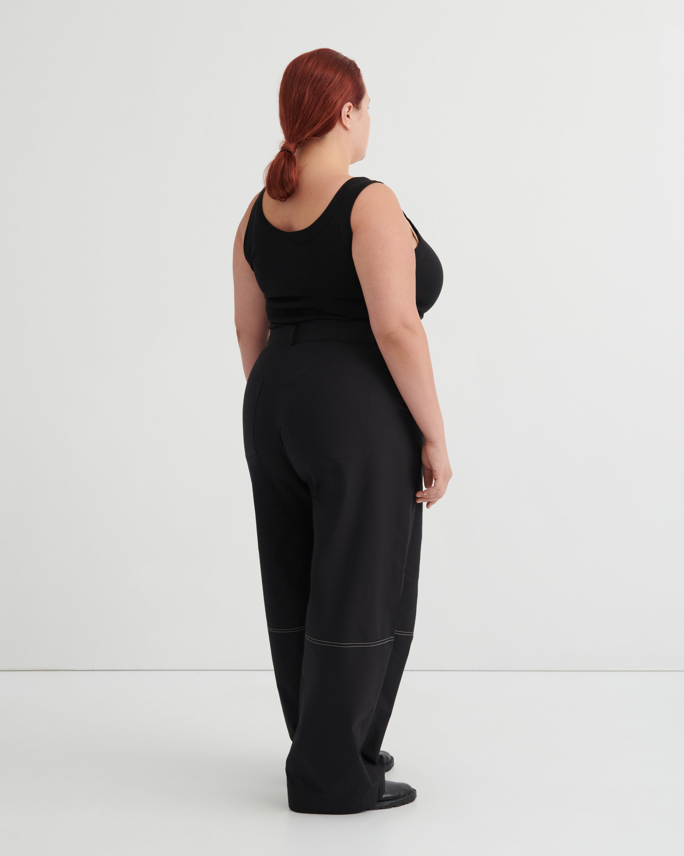 Person wearing a black tank and black pants against a white background