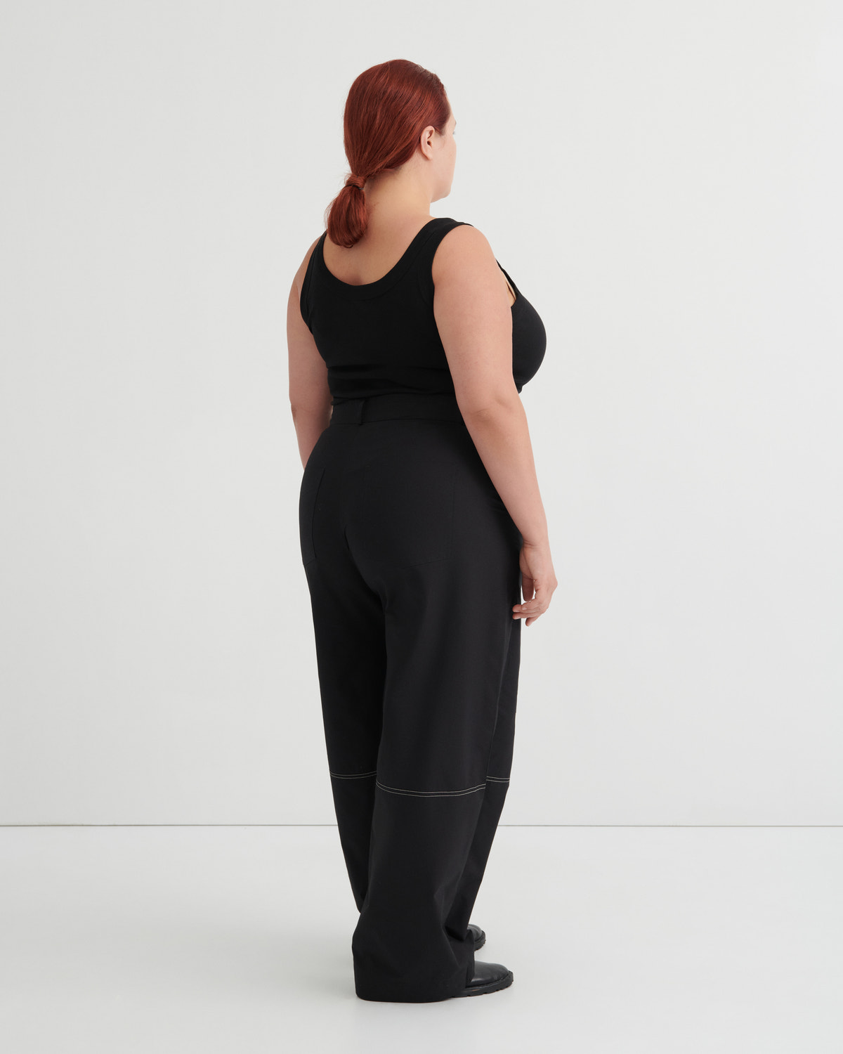 Person wearing a black tank and black pants against a white background