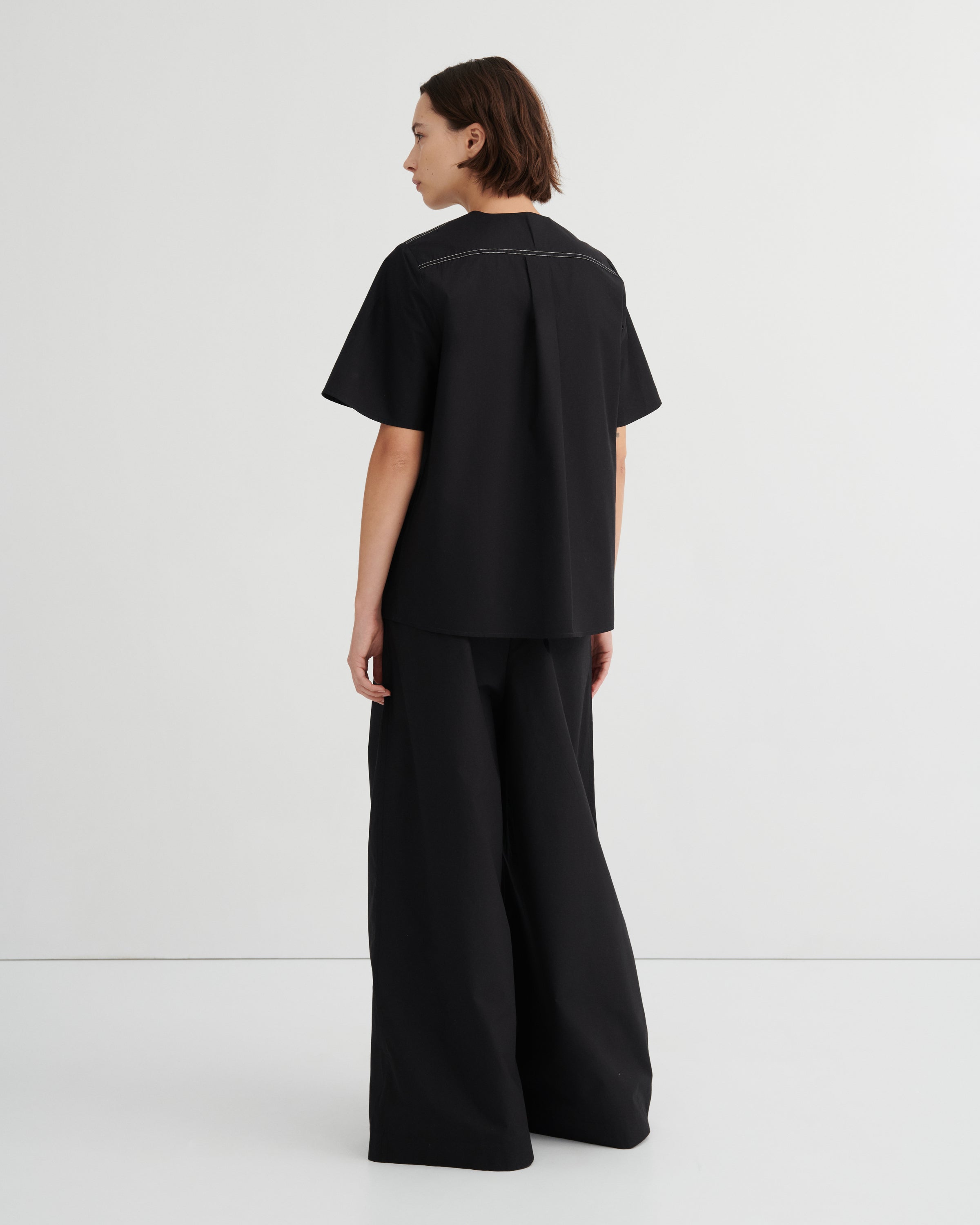 Person wearing a black outfit with wide-leg pants on a white background