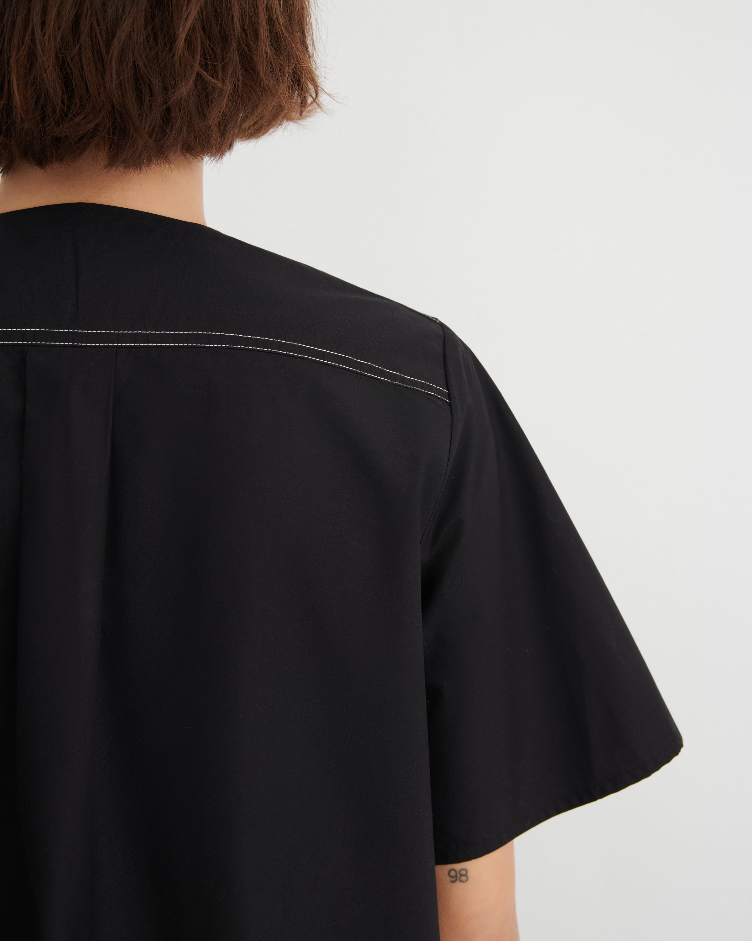 Black shirt worn by a person on a white background