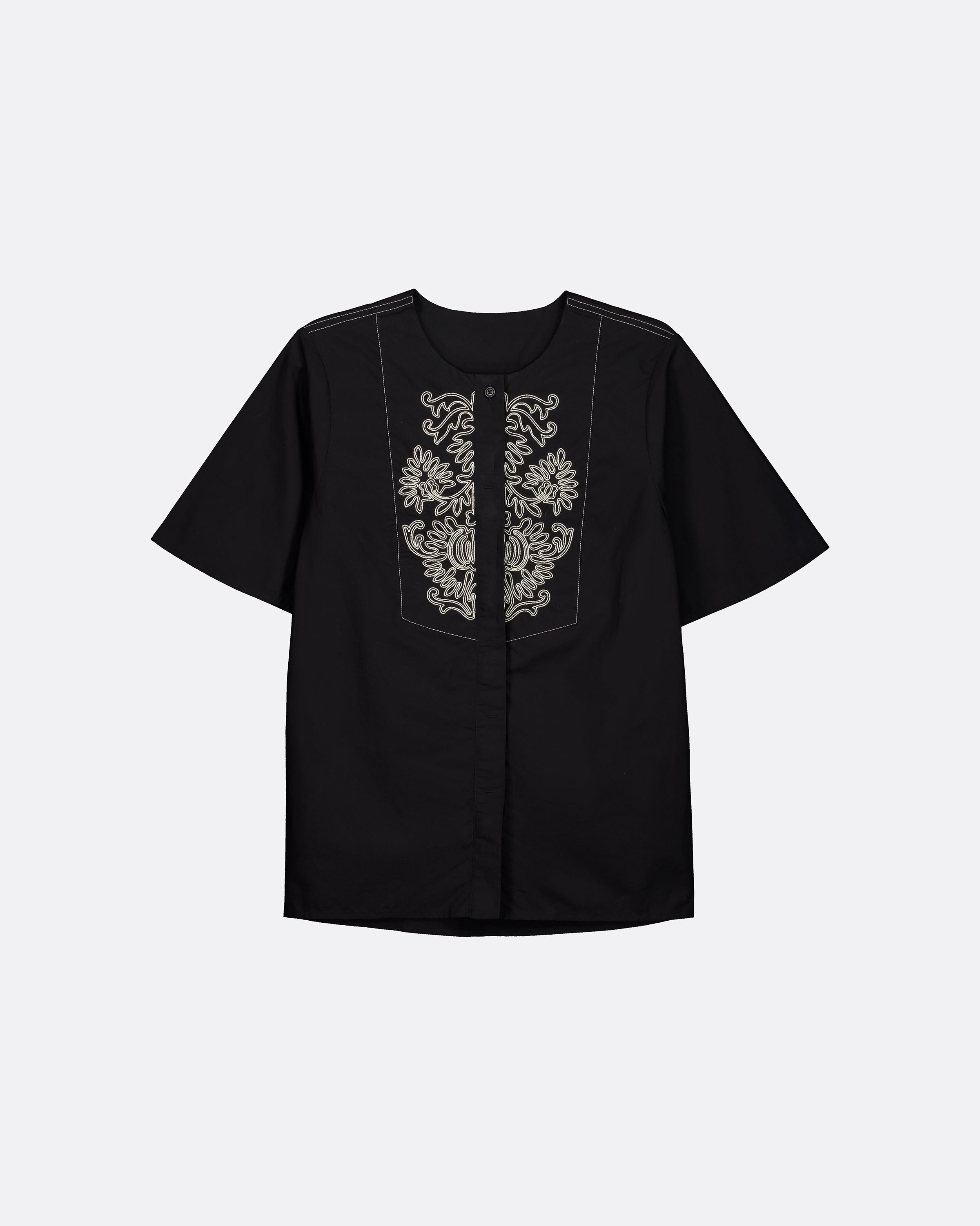A black short-sleeve button-up shirt with ornate white embroidery on the front chest panel, displayed against a light gray background.