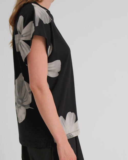 A women wearing a black tee with white floral print and black wide leg pants.